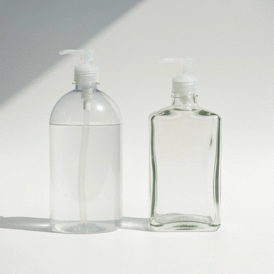 Side-by-side comparison of plastic and glass hand wash bottles, illustrating their differences in weight and durability.